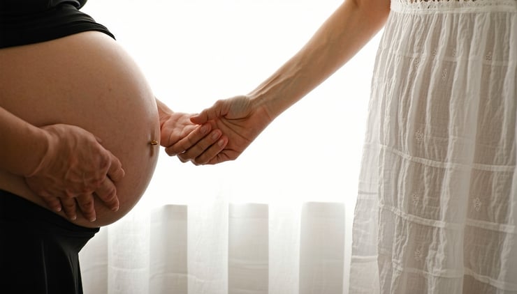 Doula holding expectant mother's hand, offering comfort in a peaceful, faith-inspired birthing room.