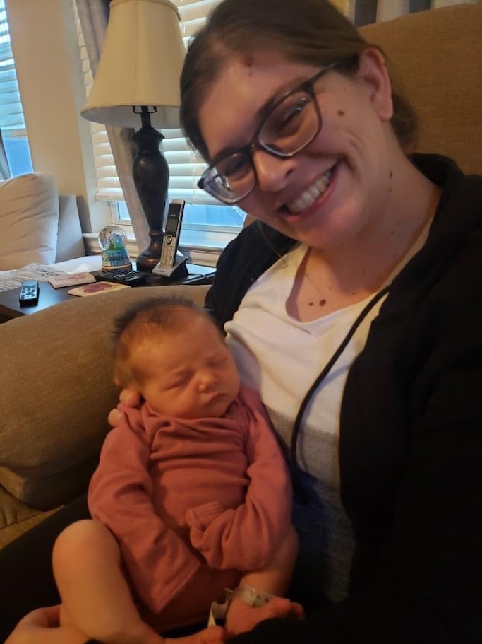 Doula Melanie Powell holding a newborn baby and smiling 