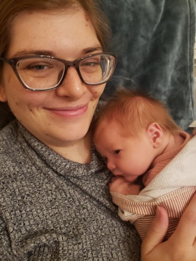 Doula Melanie Powell holding her newborn baby smiling